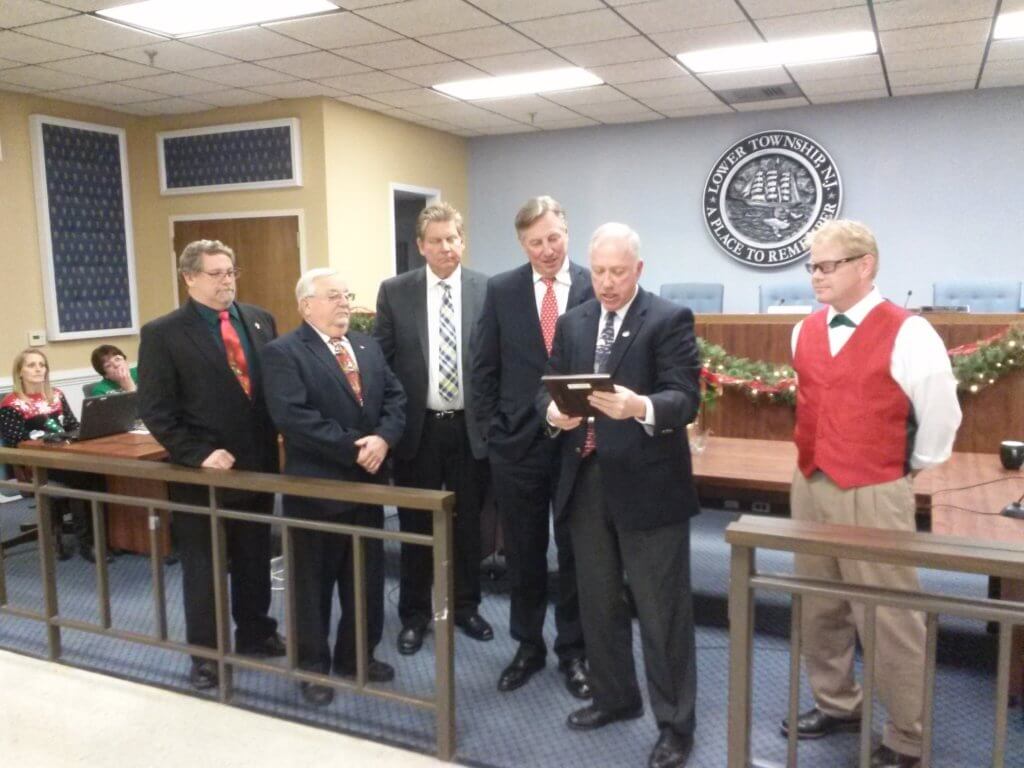 Lower Township Mayor Michael Beck reads citation given Dec. 19 at his final council meeting. Looking over his shoulder is Deputy Mayor Norris Clark. Others