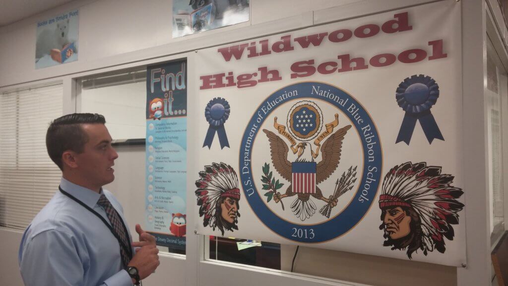 High School Principal Philip Schaffer explains a sign denoting Wildwood High School's Blue Ribbon status. The sign was designed by students.