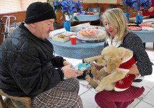 Summer and volunteer Peggy Gretz pass out a wrapped Christmas Gift to Oceana Rehabilitation Center resident Mike Worth.