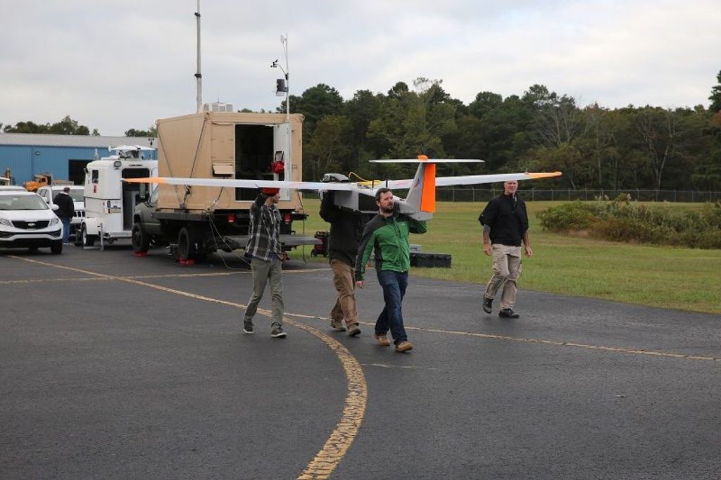 Crew members carry the AATI’s drone