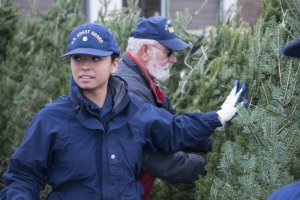 Petty Officer 3rd Class Anita Stahley helps stack trees during the annual Trees for Troops event held onboard the Coast Guard Training Center Cape May