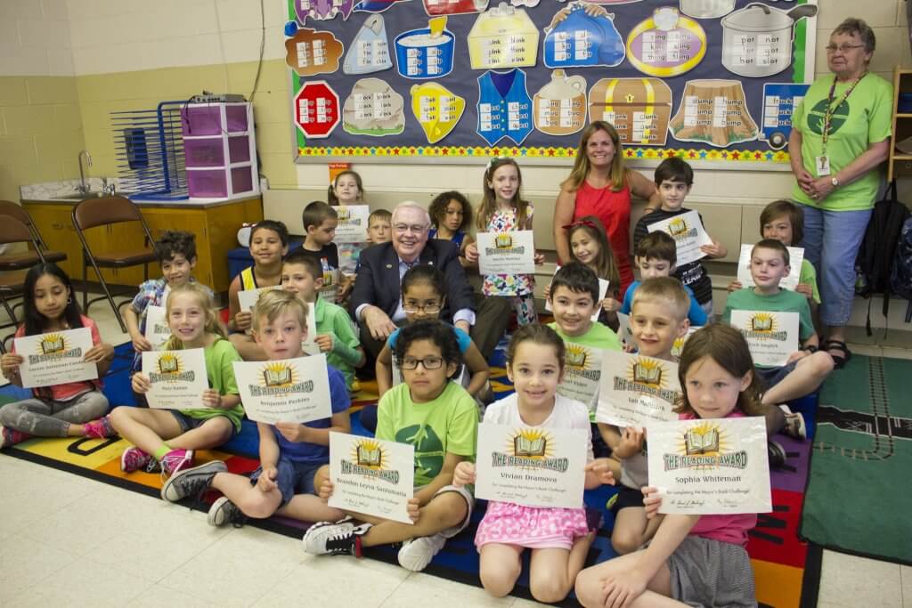 First grade teacher Stephanie Newman and students pose with Mayor Mahaney displaying their program certificates