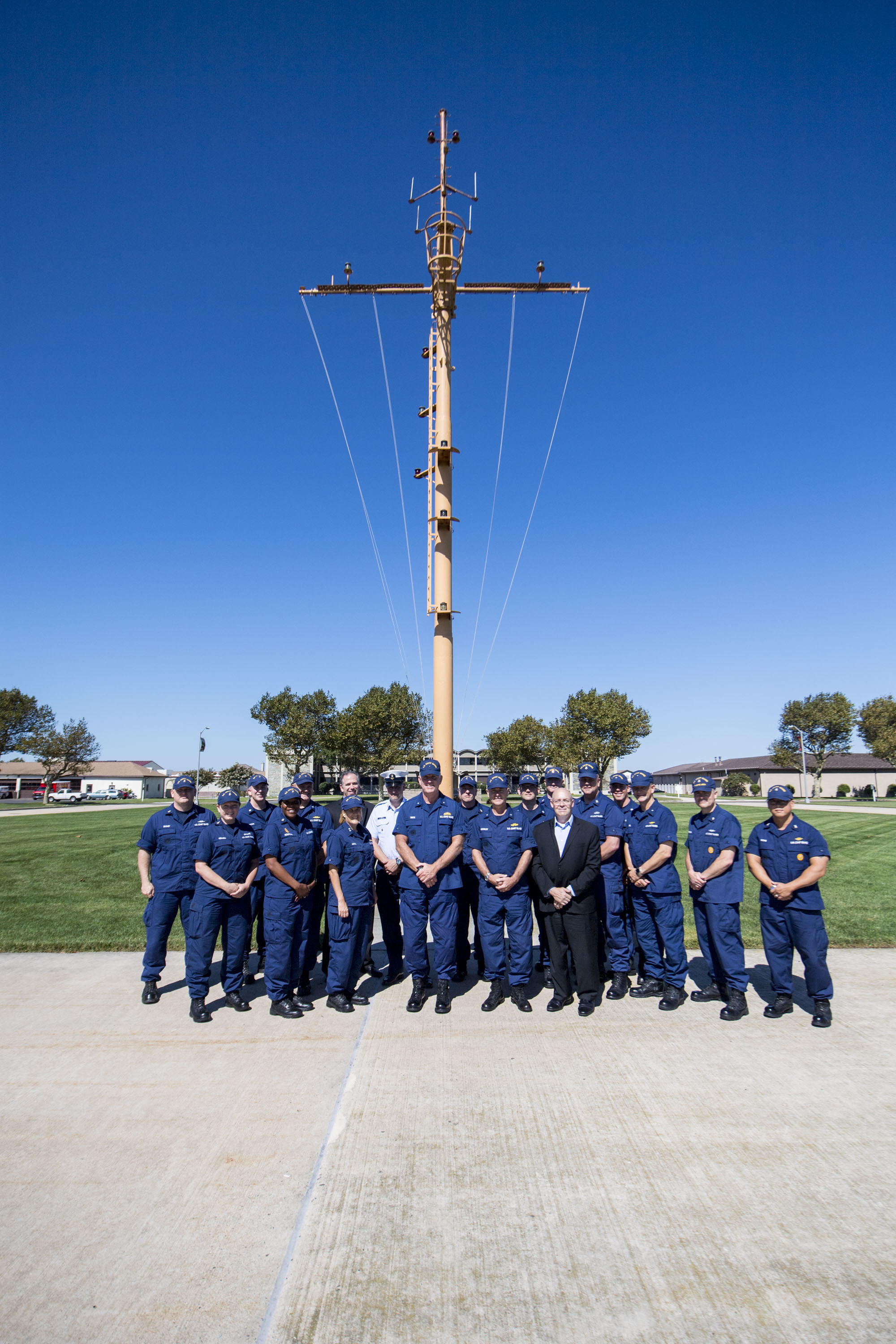 The Board of Adviors pose for a photograph in front of the Coast Guard Cutter Spencer's mast at the Coast Guard Training Center Cape May