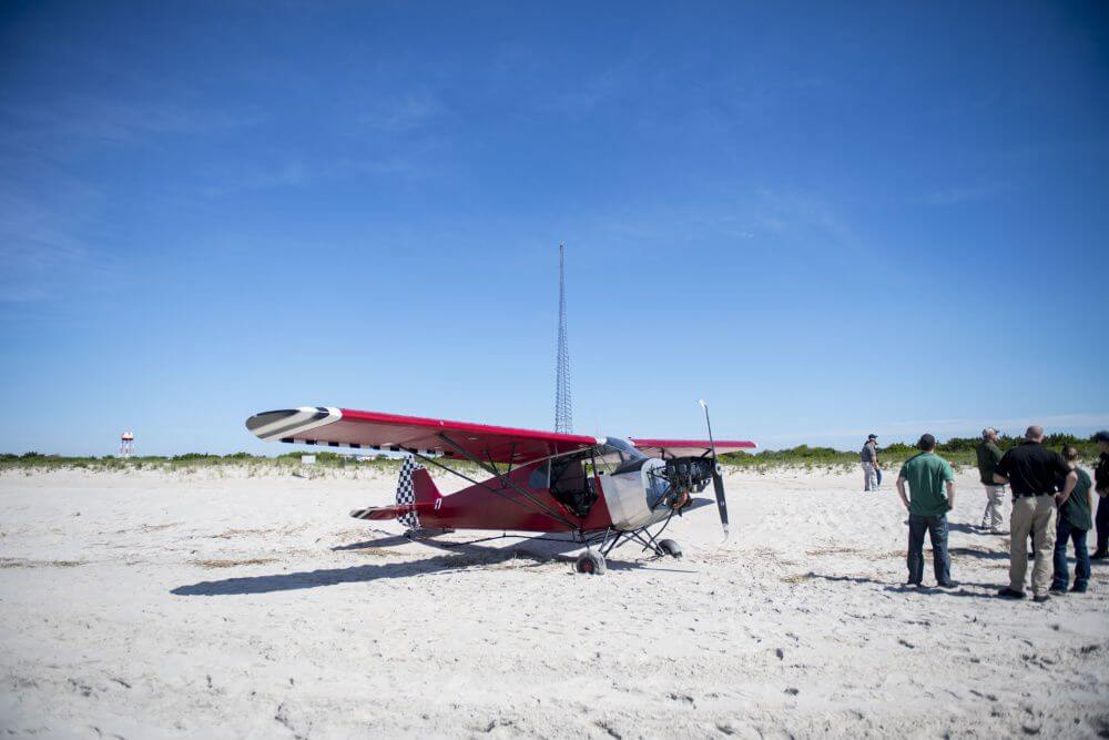 Coast Guard personnel and other various agencies stand in front of a plane on a secured beach on the southeast side of Training Center Cape May June 25 after it landed illegally and the pilot ran off.