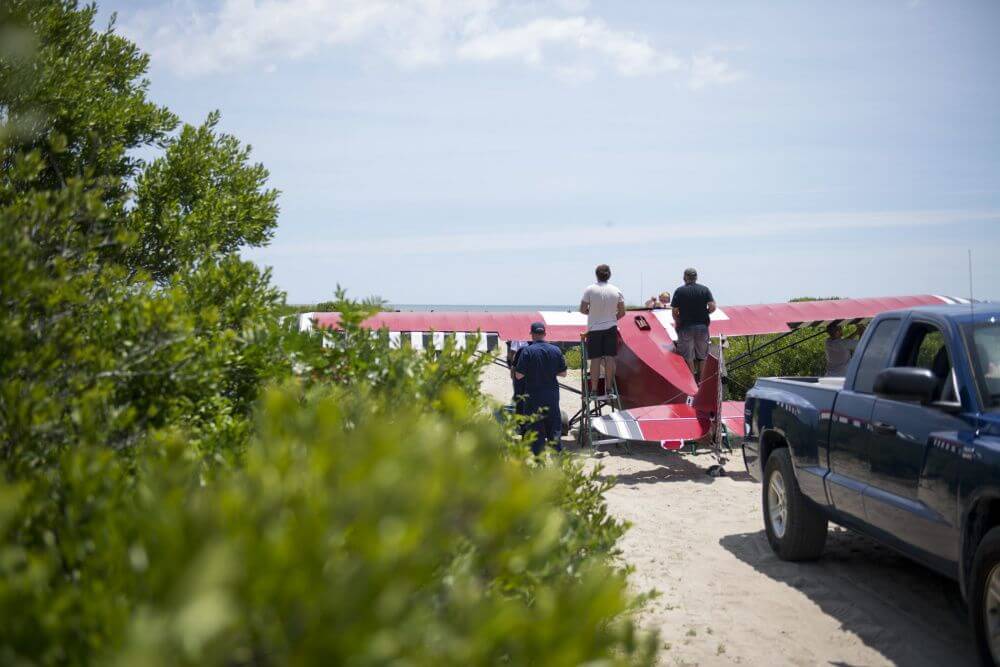 Mechanics work to disassemble the wings on a prop plane June 25 that illegally landed on a Coast Guard beach. 