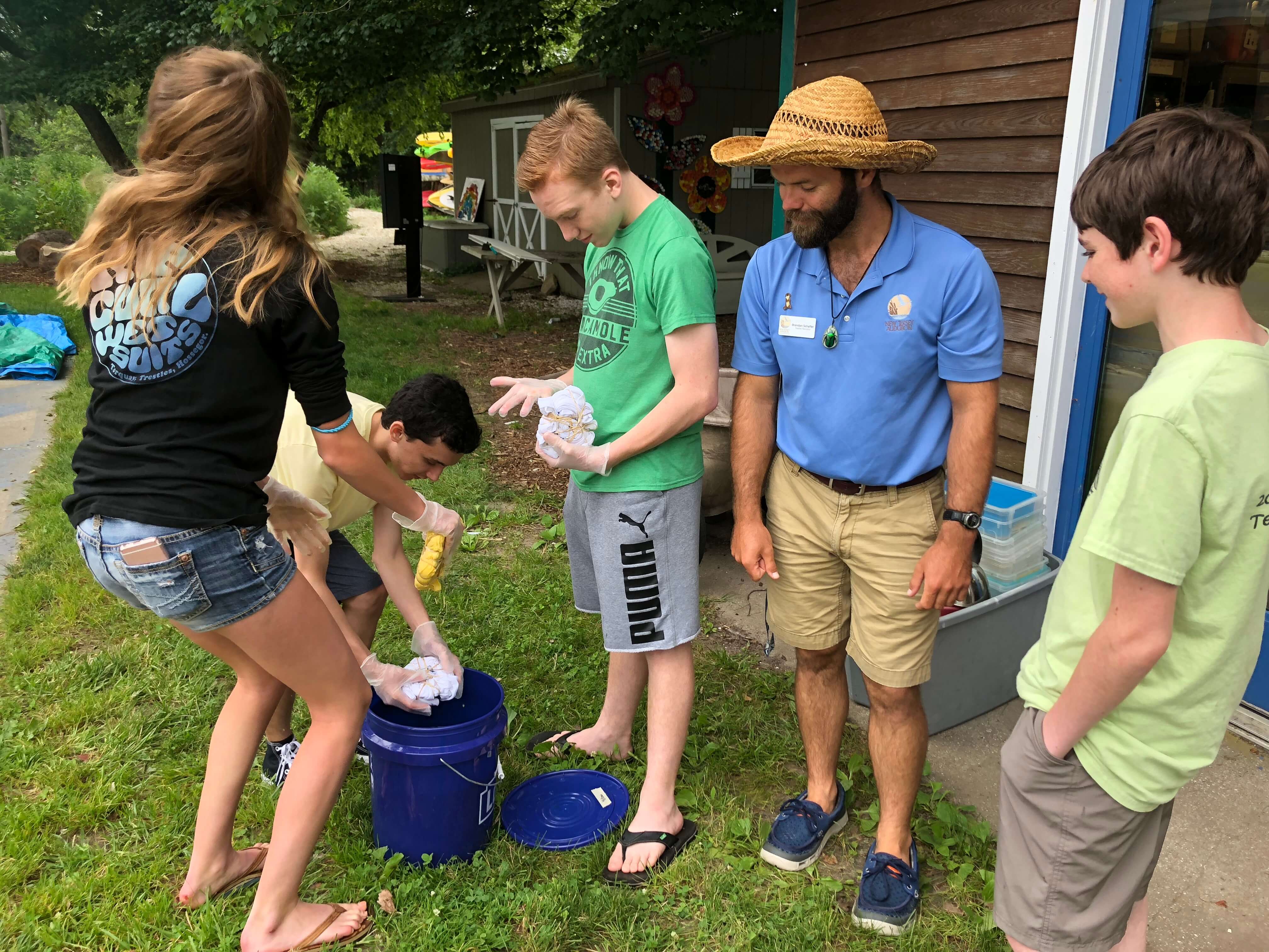 This year’s teen leaders concluded their training by tie-dying their staff T-shirts. Nature Center Camp Director Brendan Schaffer (in hat) gives helpful advice to (from left) Isabella Aftanis