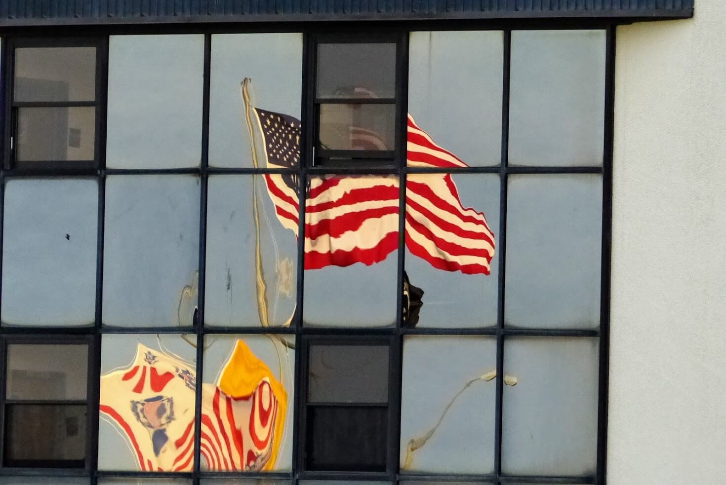 The American and Coast Guard flags are reflected in windows of building at Coast Guard Training Center