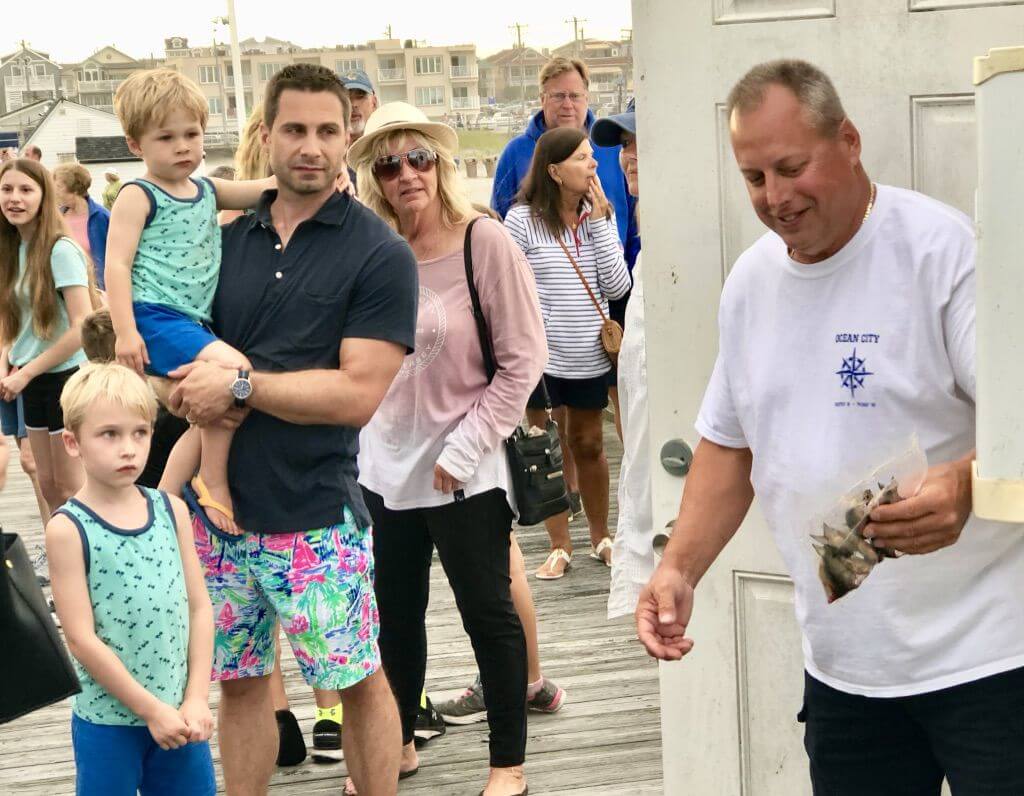Ocean City Fishing Club member Dan Moore shows a wary youngster some of the bait pier anglers use at the club's recent open house