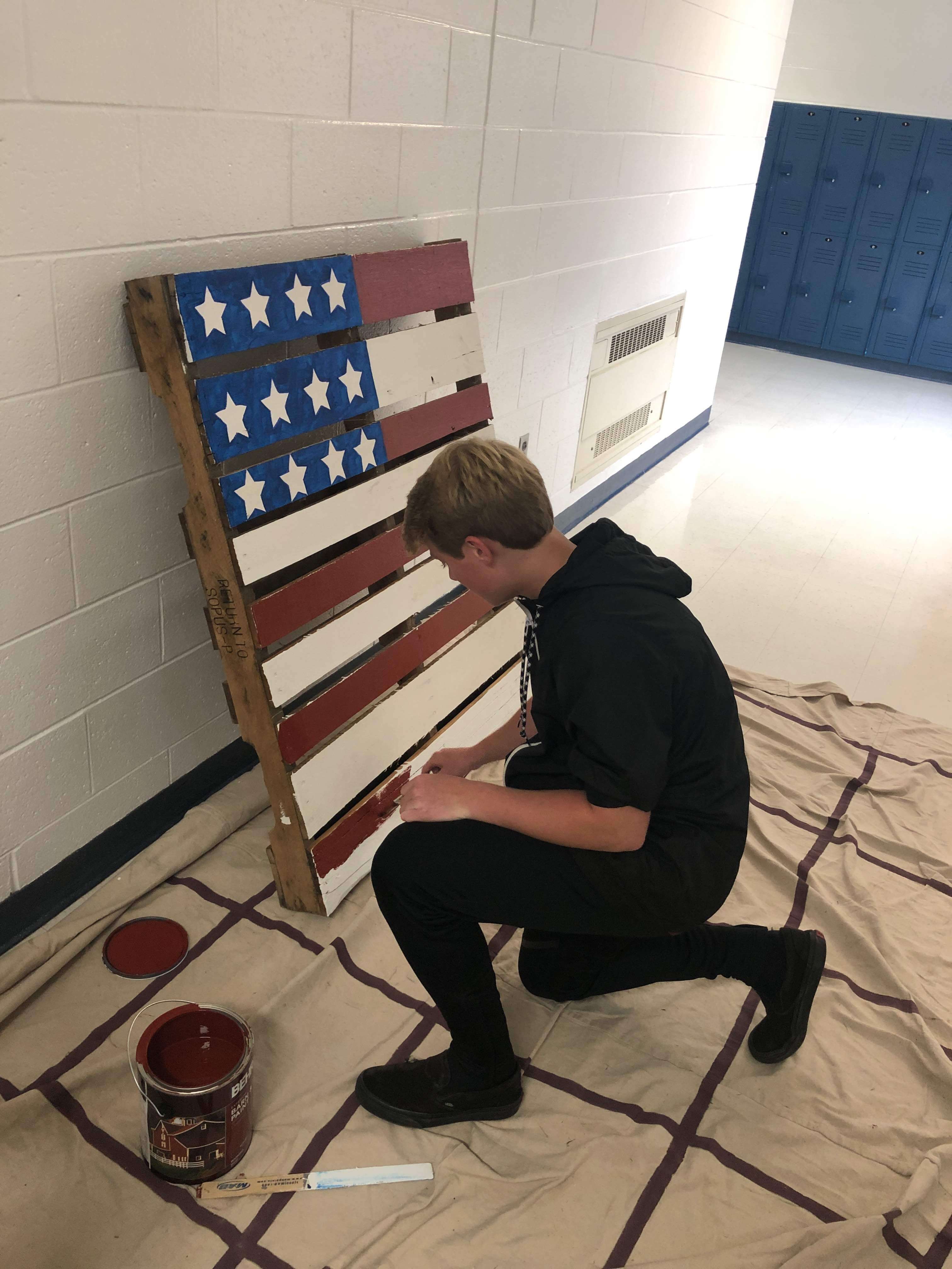 Colin Gery paints stripes on the American flag pallets.