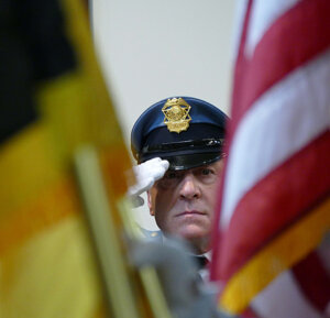 Sgt. 1st Class Thomas Hegarty with the Sheriff's Office Honor Guard salutes during singing of national anthem Jan. 3 by Treasa Hayes