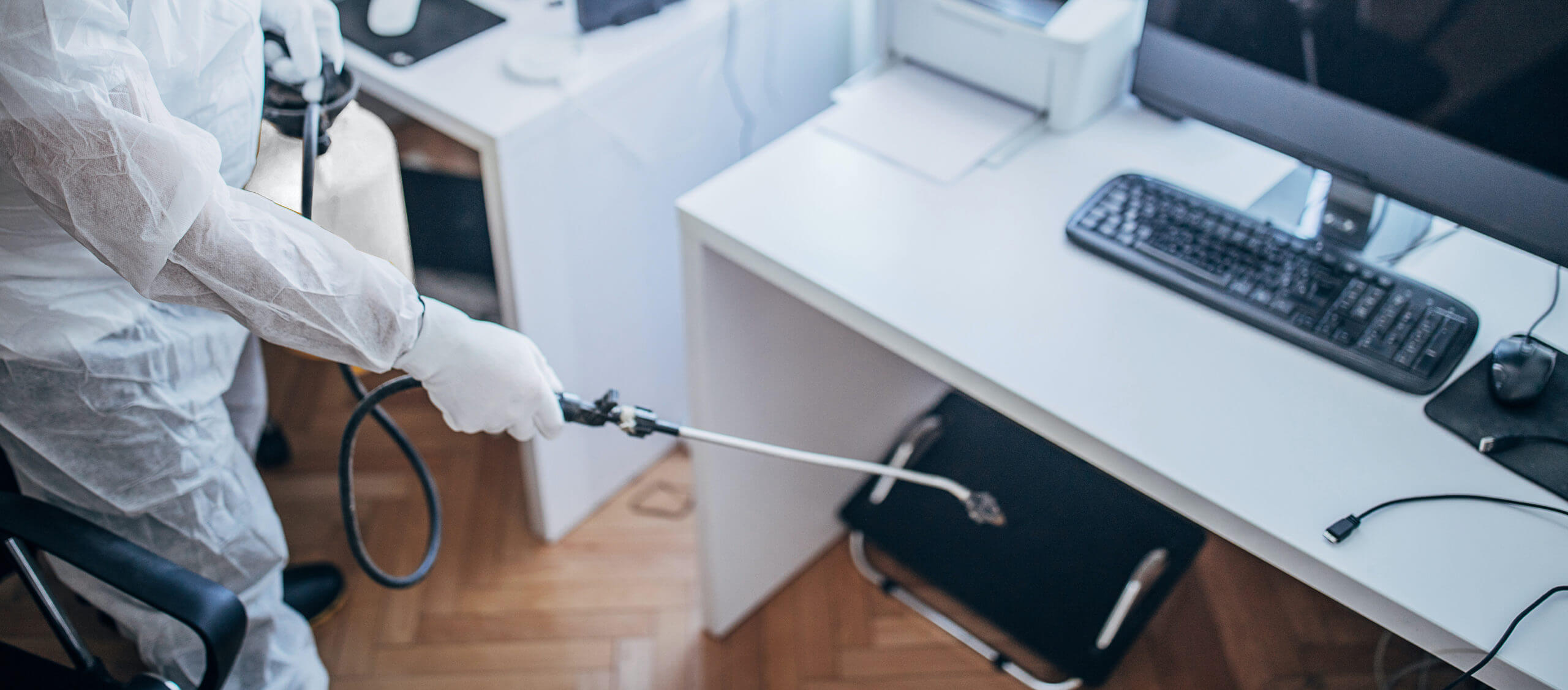 One man in protective suit disinfecting office work space