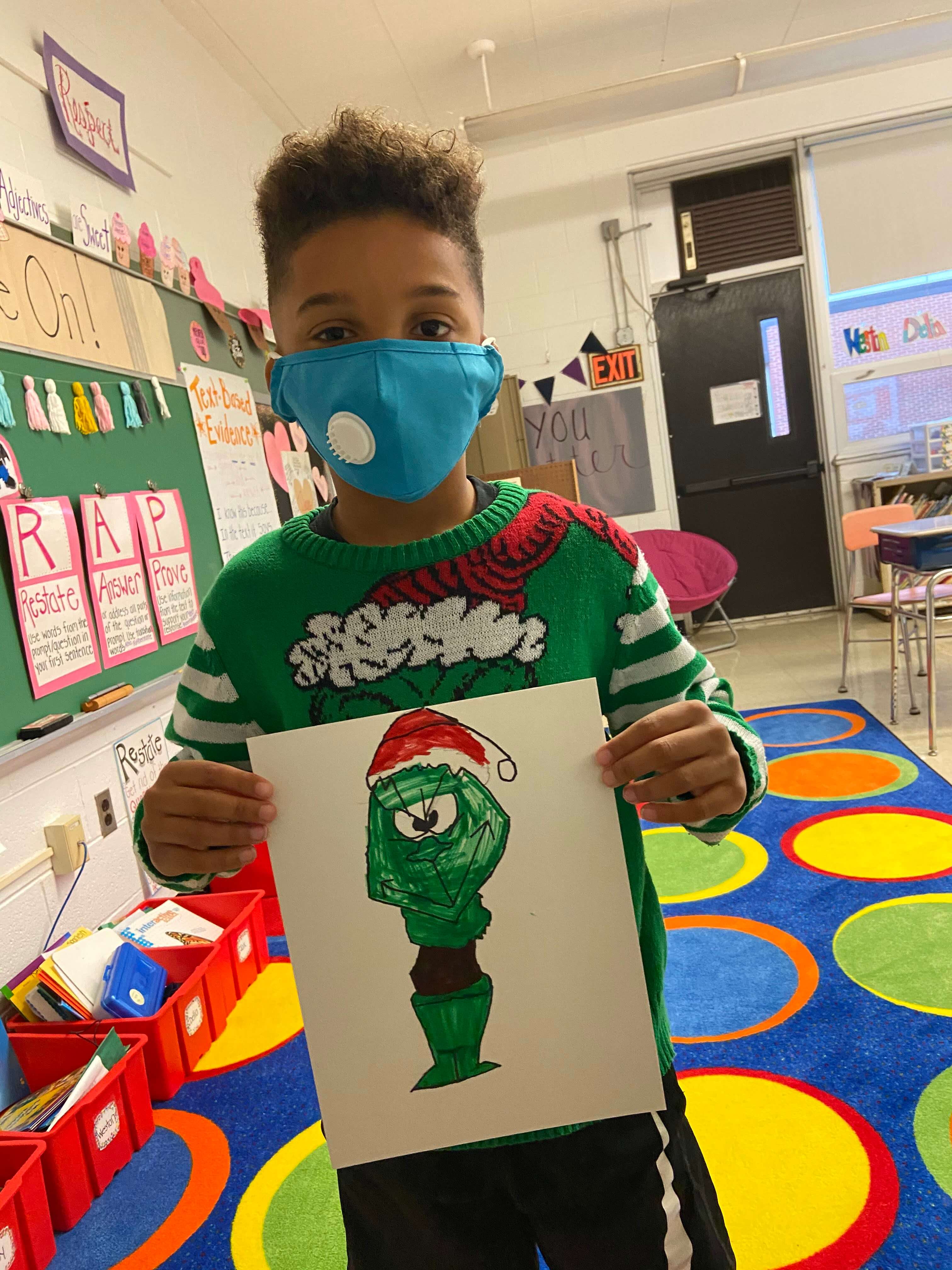 Third grader Carter Evans shows off his Grinch drawing during the third grade's annual Grinch Day