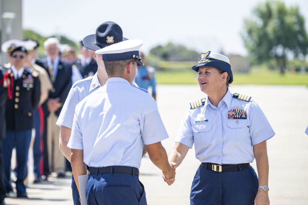 Capt. Sarah "Kathy" Felger congratulates a graduate during ceremonies . She has had a variety of onshore and at sea assignments