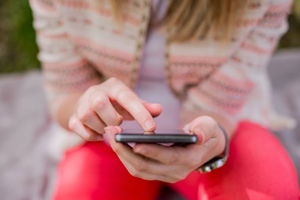 Young Girl Hold Phone - Shutterstock