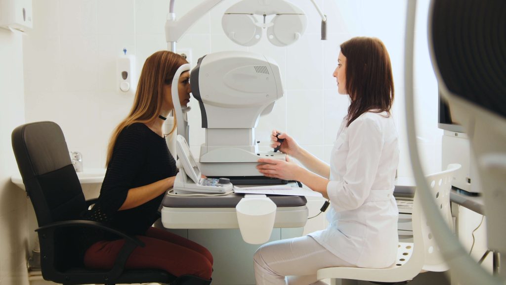 Ophthalmologist examining young woman's eyes in medical center