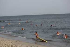 Participants rush into the water to paddle to a stake boat past the jetty during the paddling portion of the Cape May Point Women’s Lifeguard Challenge July 28.   
