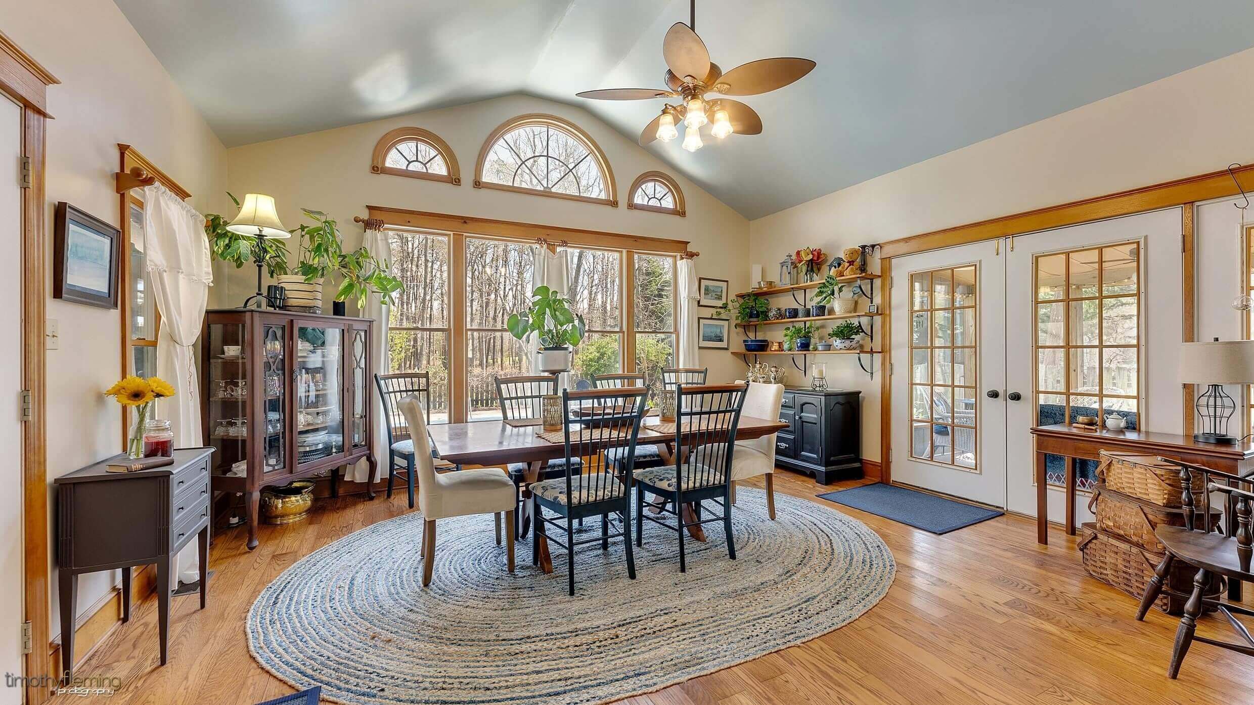 The dining room has large windows that reveal nearby trees. 