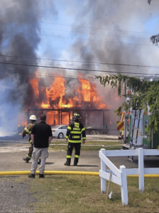 The smoking remains of 7 W. 3rd Avenue are seen between fire trucks June 29