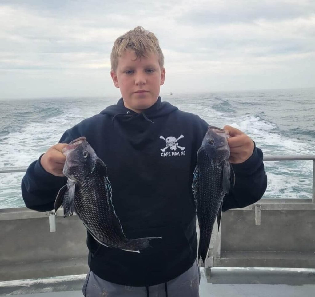 A young angler with two nice sea bass. 