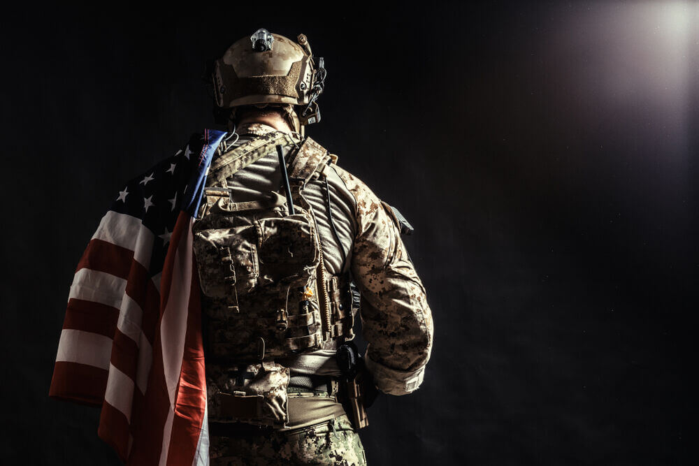 Soldier with flag over shoulder away from camera