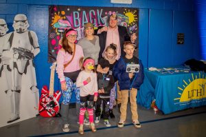 A Cape May County Family posing in front of the 80s banner during the first-ever Lower Township Healthy Youth Coalition Family Dance Party. 