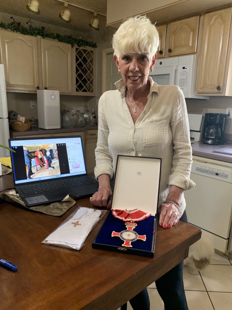 Donna Cancila Keating is shown in her kitchen back in North Cape May after traveling to Italy to be damed for her work in teaching women self-defense. Shown before her is the cross of her “knighthood” and the white gloves she wore for the ceremony.