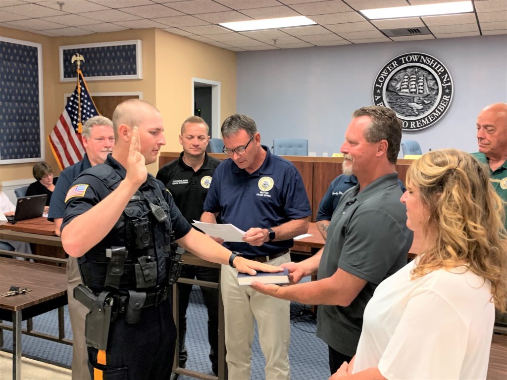 New Lower Township Police Officer Steven Gindville takes the oath of office from Mayor Frank Sippel as his father