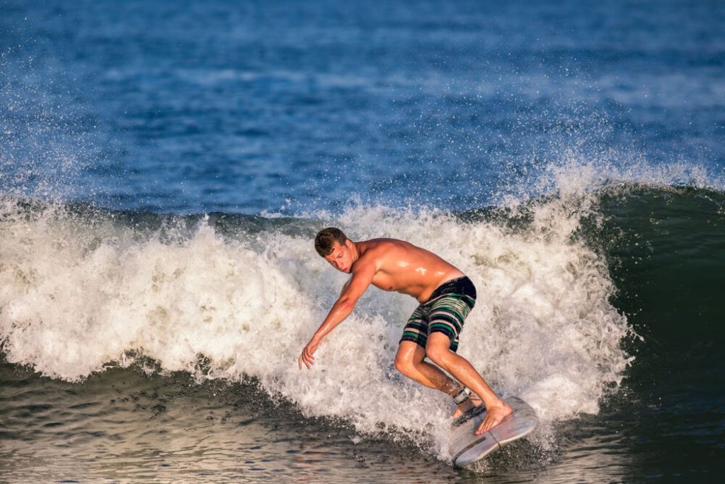 Shown is a stock image of a surfer at a Jersey Shore beach.