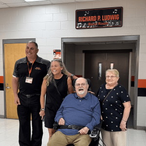 MTPS Superintendent Dr. David Salvo, Jennifer Tyndall (daughter), Richard Ludwig and Antoinette Ludwig (wife) stand with the new signage for the Richard P. Ludwig Band Room.